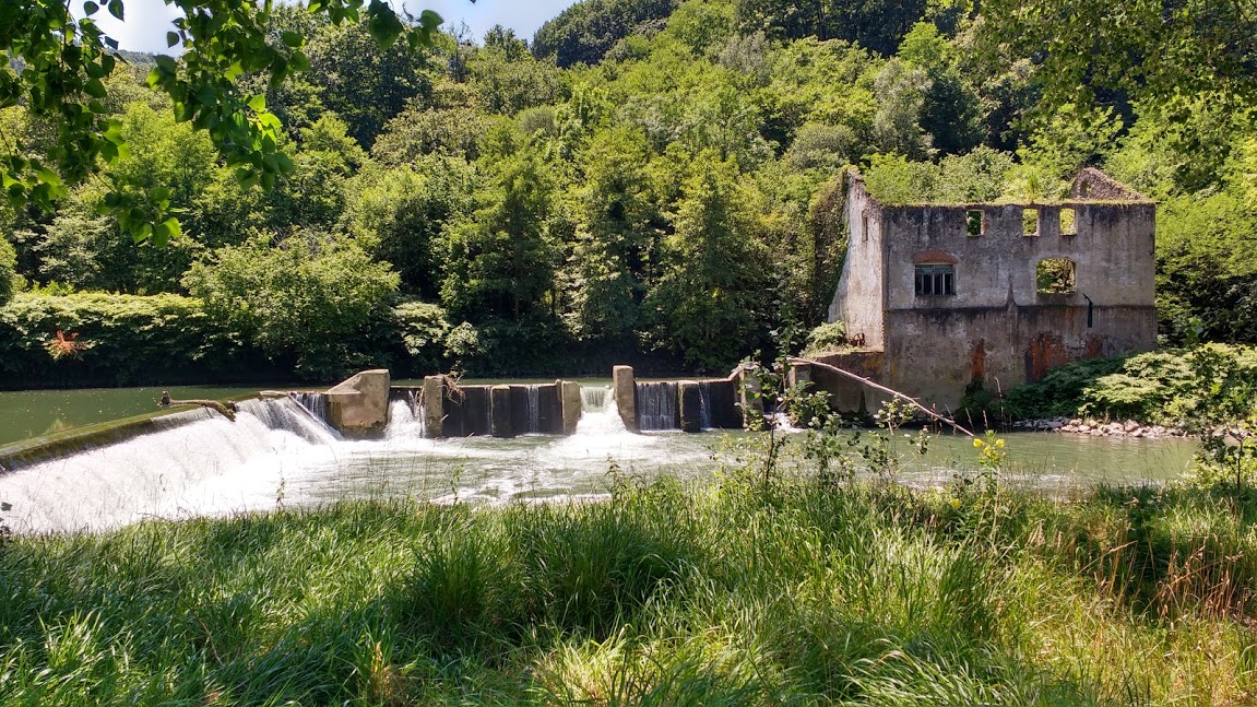 El edificio en ruinas de la vieja central de Orbeldi y la presa, que sigue en pie y constituye un importante obstáculo para la fauna.